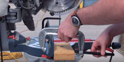 A c-clamp being used on a scrap piece of wood. This is creating a stopper for the miter saw.